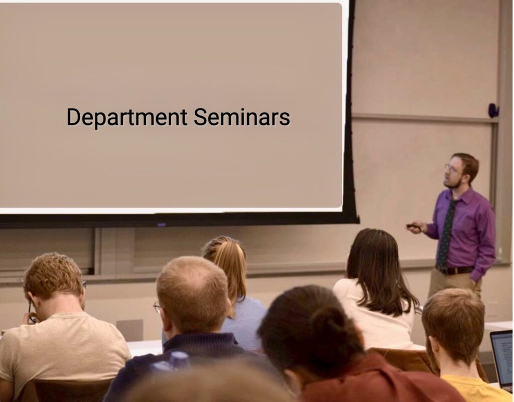 Professor presenting a seminar to an audience. All are looking at the projection screen as the professor talks about what they are seeing. The image on the screen are the words "Department Seminar"