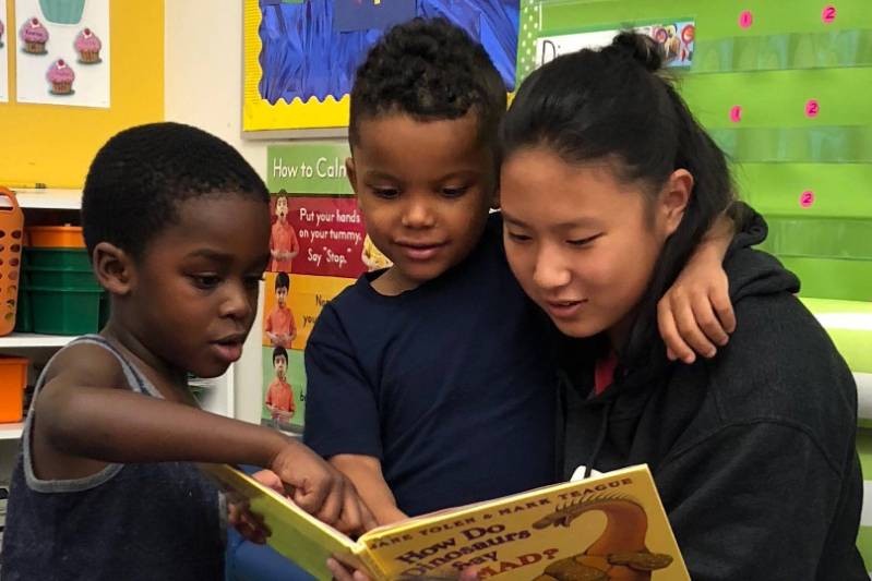 College student reading to two grade school children