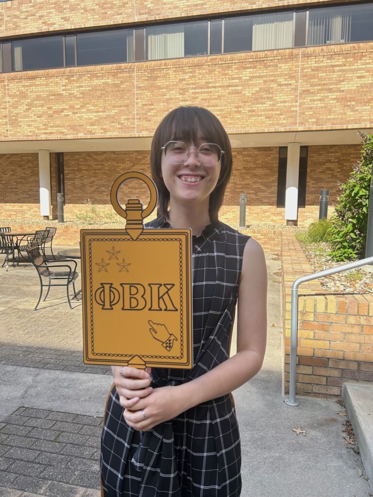 a 2025 Inductee holding the PBK key smiles at the camera in Scheide Music Center