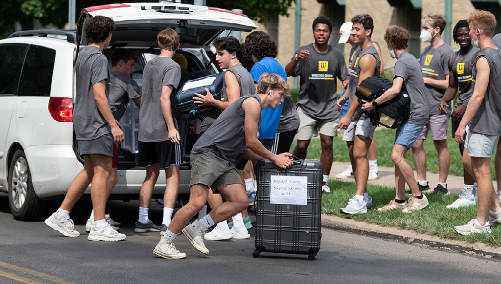 Students helping take items out of a car
