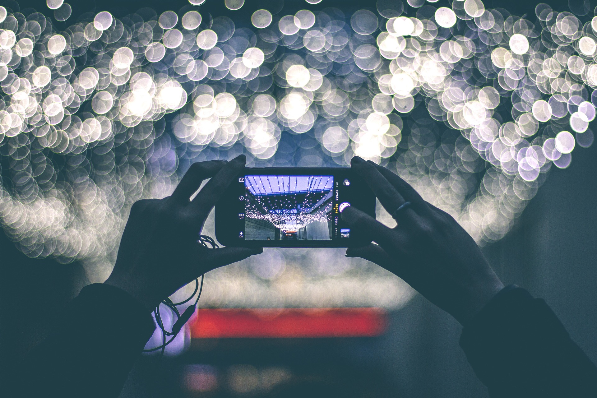 Image of a person taking a photo blurred lights with their phone