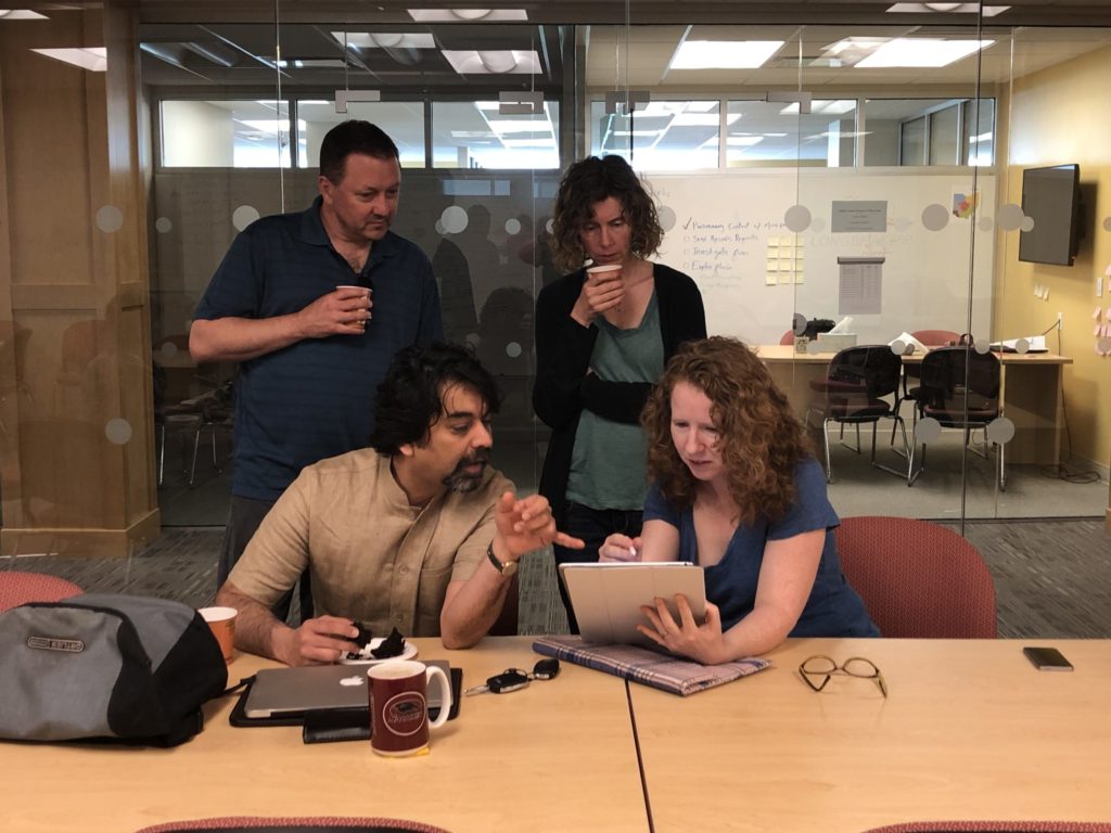 Two men and two women gathered around an iPad