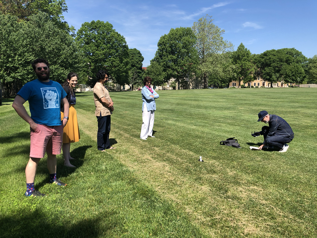 Two men and two women watching a man ready a drone for flight