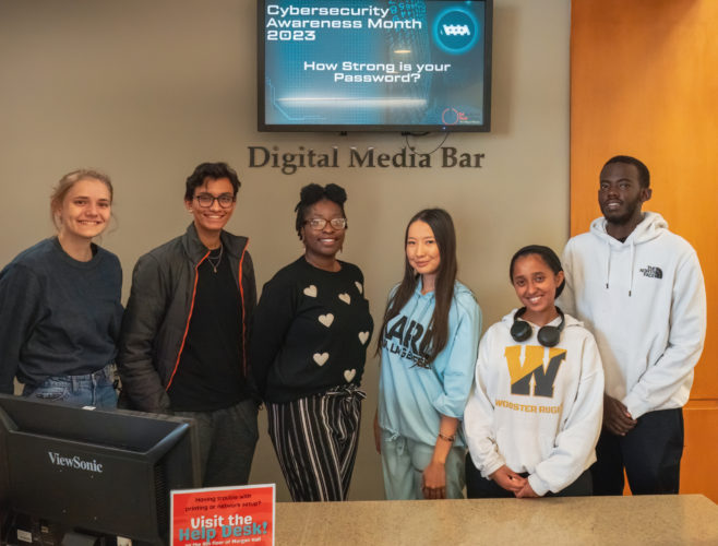 Six students photographed behind the desk at the Digital Media Bar at the College of Wooster