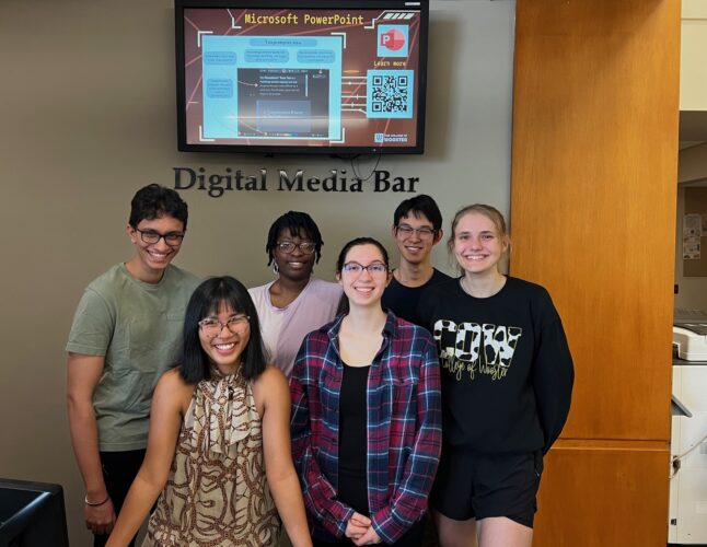 six student Digital Media Assistants smiling at the Digital Media Bar in Andrews Library