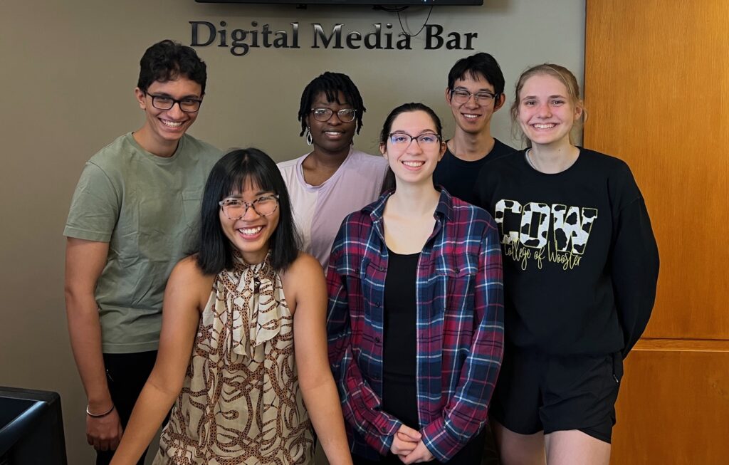six student Digital Media Assistants smiling at the Digital Media Bar in Andrews Library