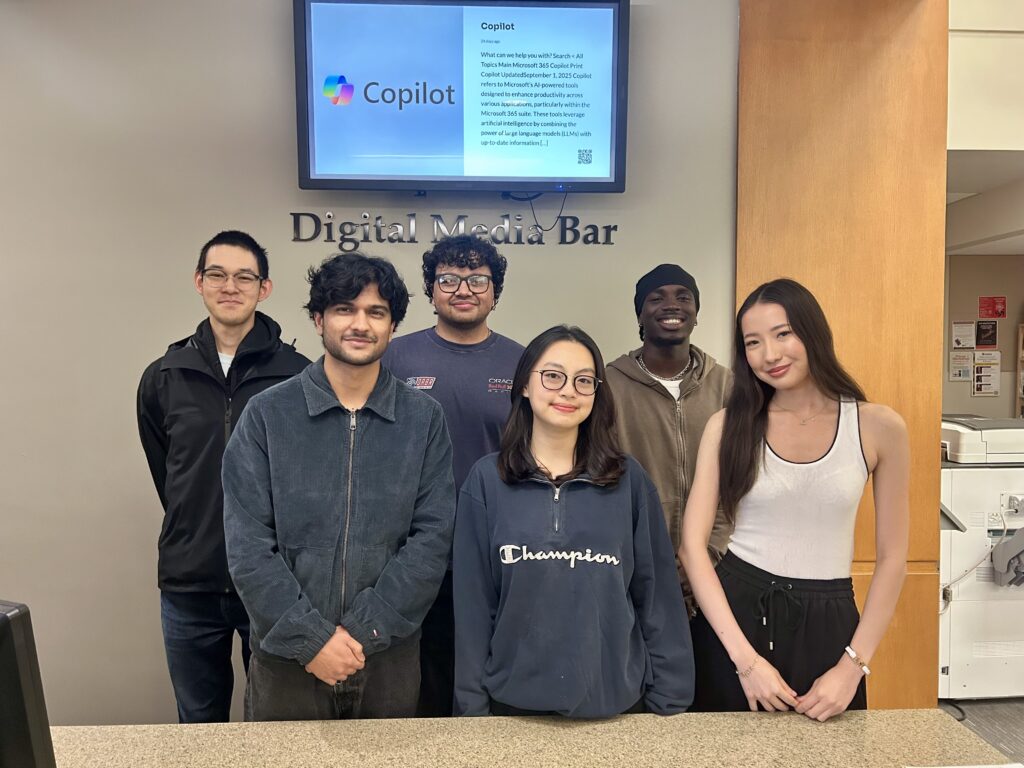 six student Digital Media Assistants smiling at the Digital Media Bar in Andrews Library